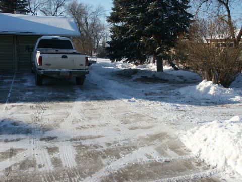 1966 Ford Bronco - A white pickup truck is parked in a driveway covered in snow and ice.