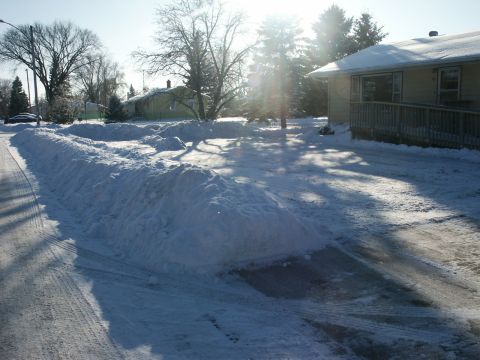 1966 Ford Bronco - A winter scene shows a snow-covered street and driveway next to a house.