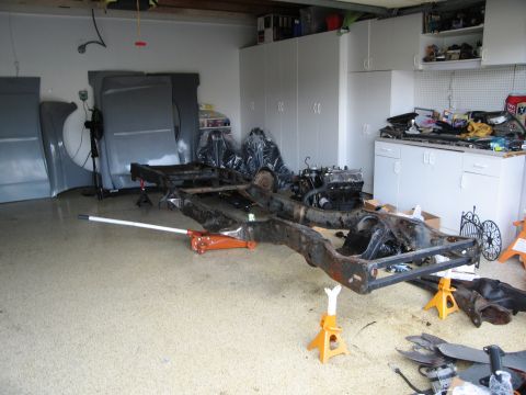 1986 Ford Bronco - The chassis and engine are disassembled and supported by jack stands in a garage setting.