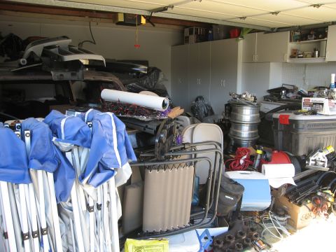 1986 Ford Bronco - A cluttered garage scene contains various stored items, including folded tents, chairs, and automotive parts, obscuring any view of a speci…