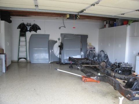1986 Ford Bronco - Car frame and body panels are disassembled in a garage.
