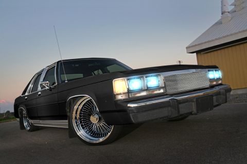 1991 Ford LTD Crown Victoria - A black 1991 Ford Crown Victoria is shown with custom chrome wire wheels and bright blue headlights.