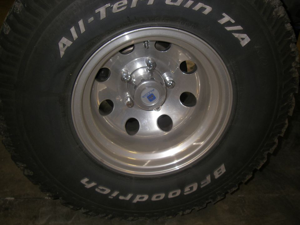 Close-up of an Alcoa wheel with BFGoodrich All-Terrain T/A tire. Center cap has Alcoa logo