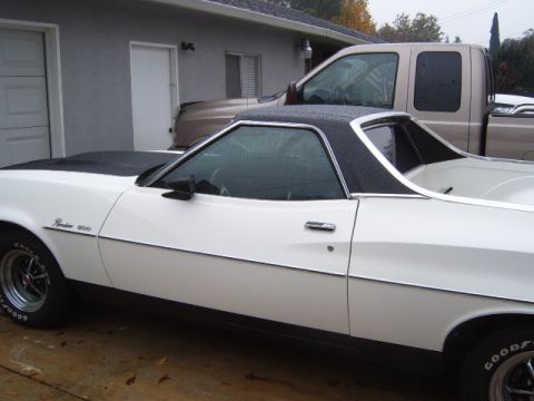 1973 Ford Ranchero - White 1973 Ford Ranchero with a black vinyl top and hood stripe, parked outdoors.