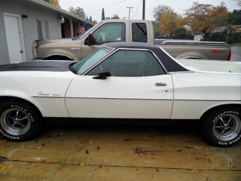1973 Ford Ranchero - A white 1973 Ford Ranchero is parked next to a tan pickup truck on a cloudy day.