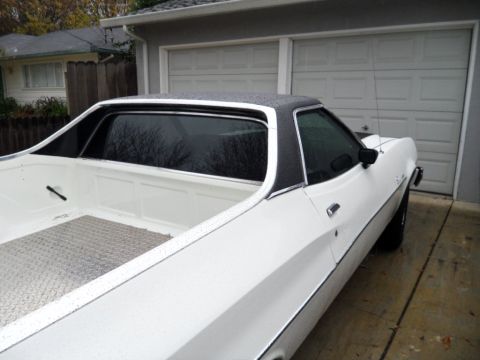 1973 Ford Ranchero - White 1973 Ford Ranchero with a black vinyl roof and diamond plate in the bed, seen from a 3/4 front angle.