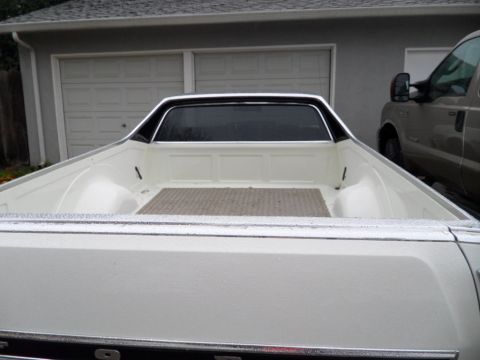 1973 Ford Ranchero - Rear view of a 1973 Ford Ranchero pickup truck bed, showing the white interior and a second vehicle parked nearby.