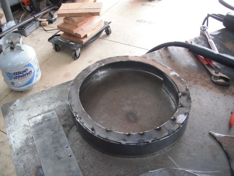 1986 Ford Bronco - A metal ring is being fabricated with welding. A propane tank and wood are visible in the background.