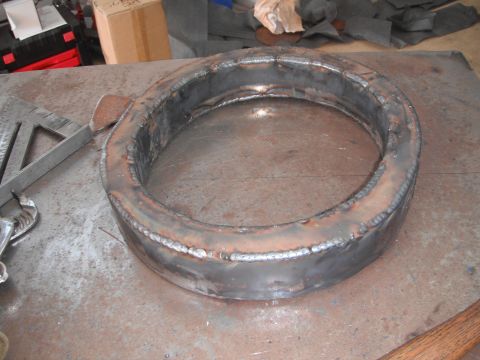 1986 Ford Bronco - A custom-fabricated metal ring sits on a cluttered workbench, showing signs of recent welding.