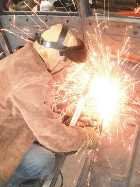 1986 Ford Bronco - A person in protective gear welds inside a vehicle's interior, creating a shower of sparks.