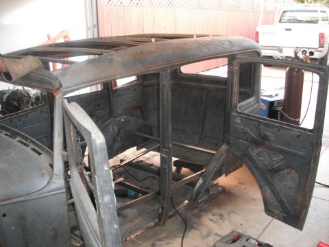 1986 Ford Bronco - The body of a vintage car, possibly a 1931 Ford Model A, is shown in a state of disrepair and restoration.