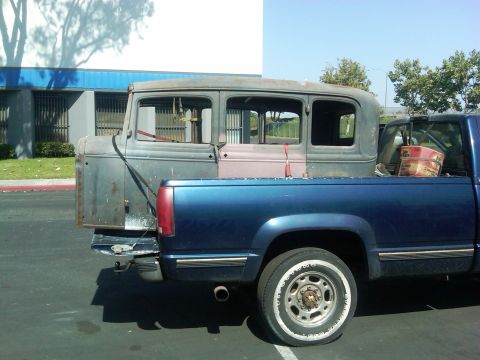 1986 Ford Bronco - Vintage car body transported in a modern pickup truck, likely for restoration or parts.