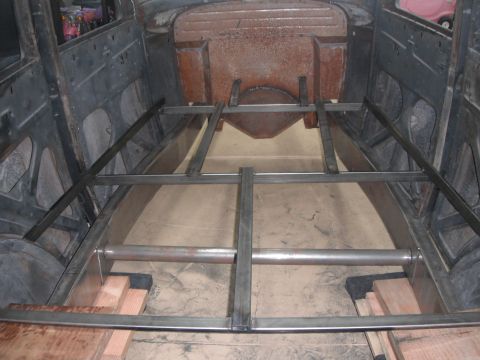 1986 Ford Bronco - The interior of a vehicle shows new metal framing being installed over the floor, with wooden blocks providing support.