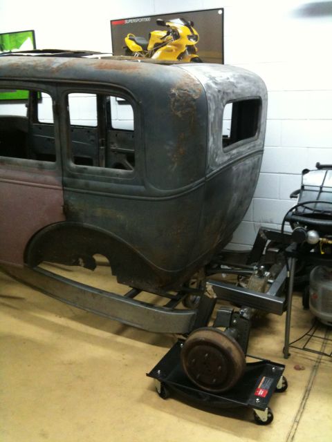 1986 Ford Bronco - Rusty body of a vintage car, possibly a 1931 Ford Model A, mounted on a stand for restoration.
