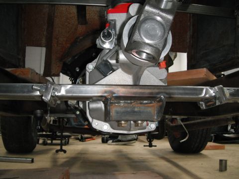 1986 Ford Bronco - Undercarriage view of a vehicle's drivetrain and suspension, a differential and driveshaft. The Supermotors.net logo is visible.