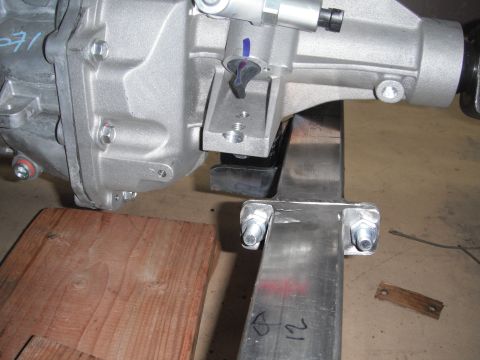 1986 Ford Bronco - Close-up of an automotive differential assembly with a metal bracket attached, supported by wood and metal.