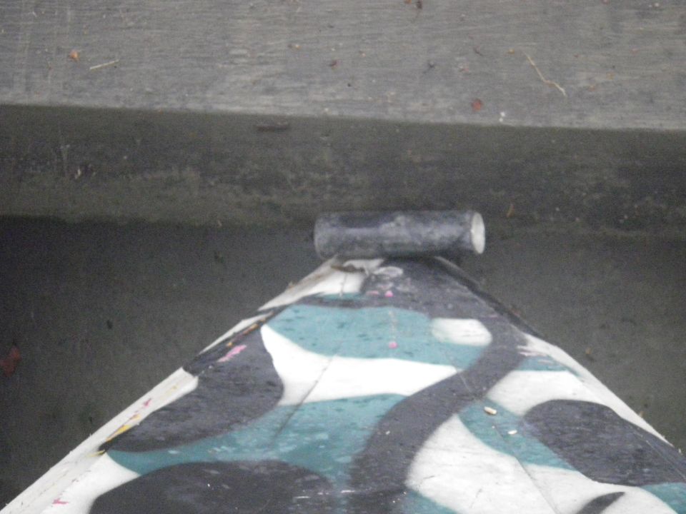 Camouflage painted object with a pipe on top, sitting on concrete