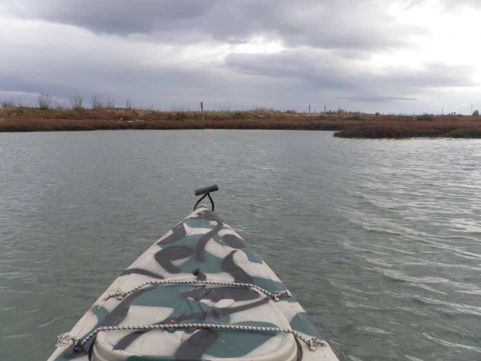 Camouflaged kayak on water under cloudy sky