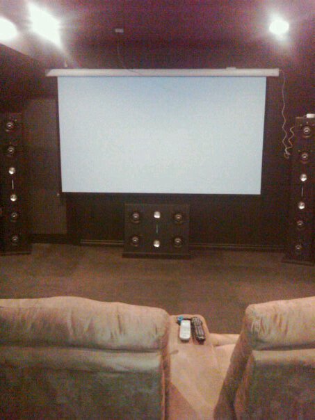 1987 Ford Bronco - A home theater room is set up with a projector screen, speakers, and comfortable seating.