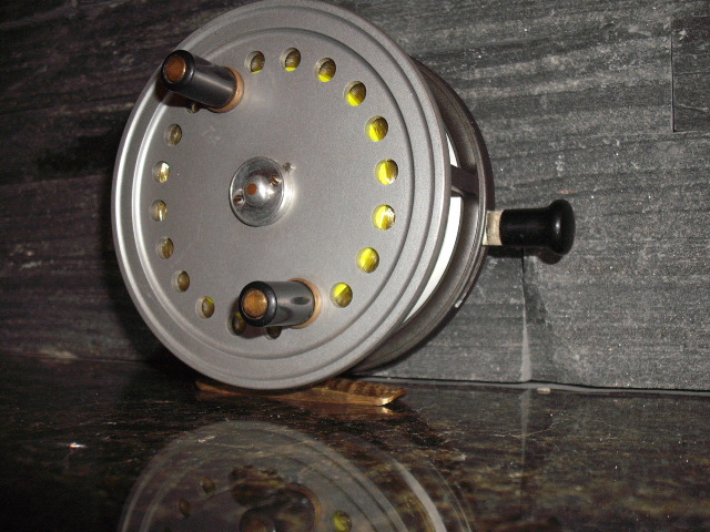 Silver fishing reel with black handle and yellow accents