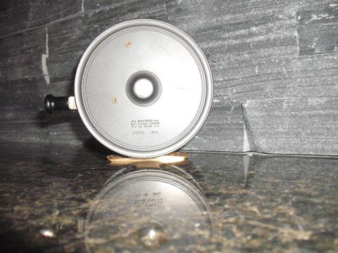 1990 Ford Bronco - A metal lid with a handle is shown against a stone wall background, reflecting on a polished surface.