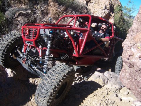 Suzuki Samurai - A driver navigates a custom-built red buggy through a challenging rocky off-road course.