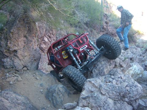 Suzuki Samurai - Off-road buggy tackling a challenging rocky trail in a desert environment.