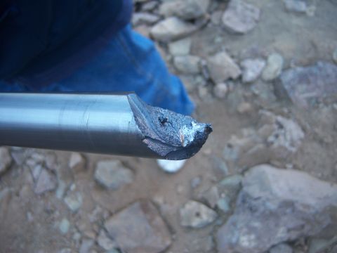 Suzuki Samurai - This image shows a close-up of a damaged metal pipe, likely a vehicle part, with a rough, broken end.