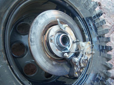Suzuki Samurai - A close-up view of a vehicle's brake rotor and caliper assembly, with a portion of a tire in the foreground.