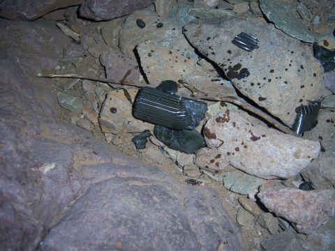 Suzuki Samurai - Debris, possibly from a vehicle, lies amongst rocks in a natural setting.