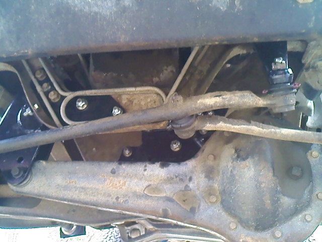 Underside view of truck suspension and steering components. Shows tie rods, ball joints, and frame