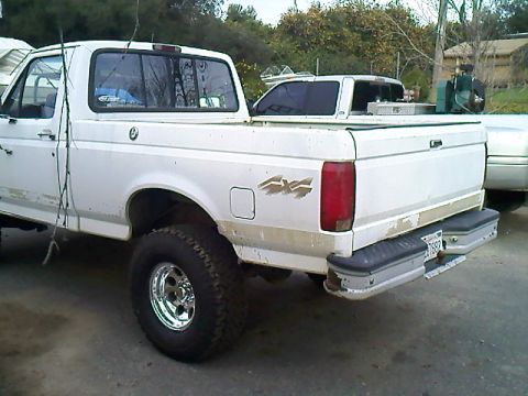 1995 Ford F-150 - A white Ford pickup truck is parked outdoors, with another vehicle visible behind it.