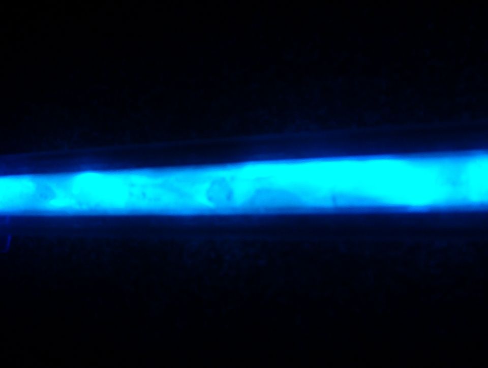 Glowing blue neon or UV-lit tube photographed in the dark