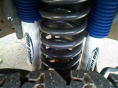1995 Ford F-150 - A close-up view of the suspension components, including Pro Comp shocks and coil springs, with a tire in the foreground.