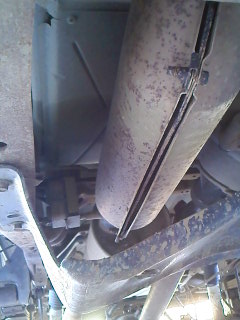 1995 Ford F-150 - Close-up of vehicle exhaust components, including a large muffler and supporting straps.