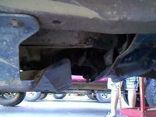1995 Ford F-150 - A close-up view of a vehicle's undercarriage, showing exhaust system parts and a person in the background.