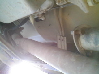 1995 Ford F-150 - Close-up view of the undercarriage and exhaust system of a vehicle, with a SuperMotors logo in the corner.