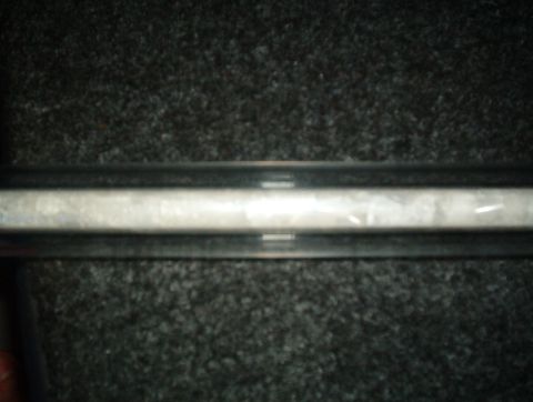 1998 Ford Taurus - A close-up view of an interior trim piece, possibly from a car, with a textured surface and dark framing.