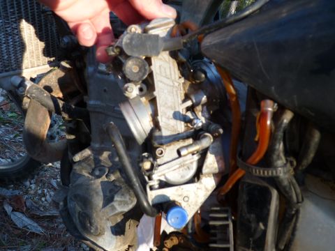 2001 Suzuki DR-Z400 - Close-up view of a motorcycle's carburetor and associated fuel lines, with a hand adjusting a component.
