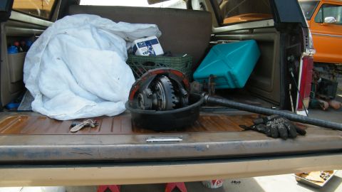 1982 Ford Bronco - Differential assembly and supplies loaded in the bed of a truck, with another vehicle in the background.