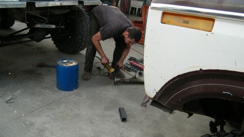 1982 Ford Bronco - A person uses an angle grinder on the body of a vehicle in a workshop setting that appears to be a garage or workshop.
