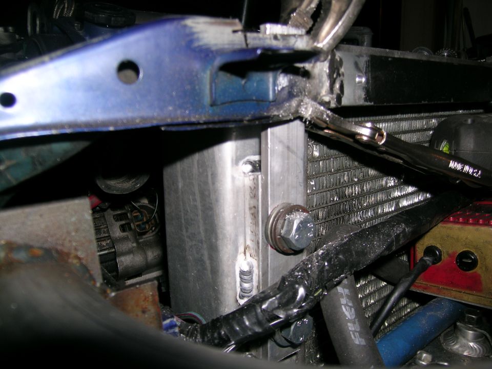 Close-up of engine bay with custom metalwork and radiator. Wrench on radiator hose