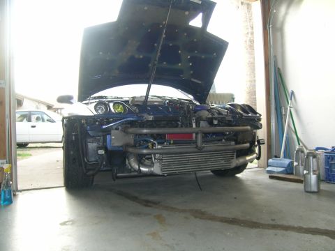1995 Ford Probe - Front view of a 1995 Ford Probe undergoing modifications, with the hood raised to expose the engine bay.