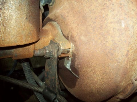 1985 Ford Bronco - Close-up view of a heavily rusted engine component, showing a metal bracket and bolt assembly.