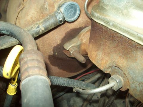 1985 Ford Bronco - This image shows a close-up view of various engine components, including hoses and a brake fluid reservoir, with visible signs of rust and…