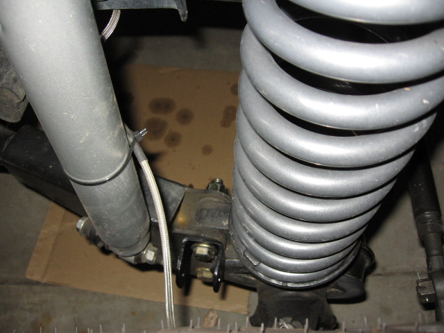 Coil spring and shock absorber with braided line at suspension lower mount
