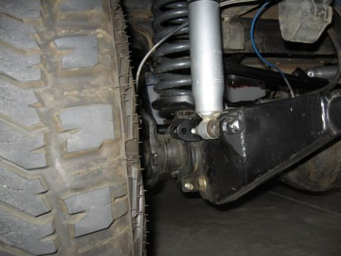 1995 Ford Bronco - A detailed view of the vehicle's front suspension system, focusing on the tire and shock absorber assembly.