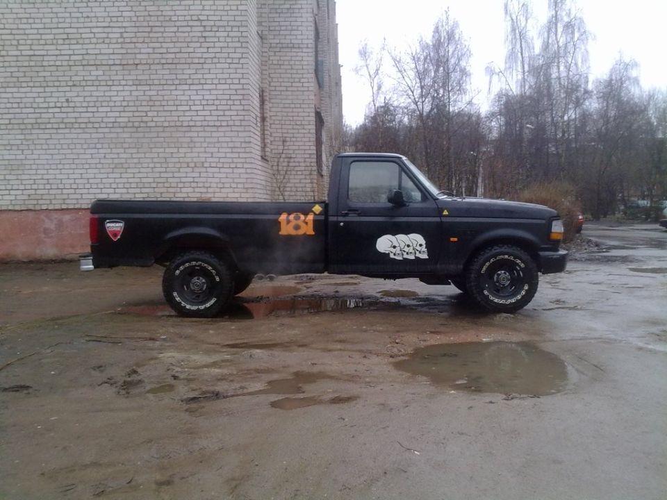 Black pickup truck with skull decals and orange '181' graphic, side view