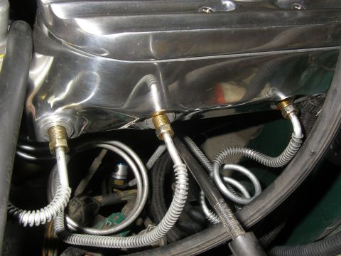 1990 Ford Bronco - Close-up of engine components, including a shiny valve cover and brake lines.