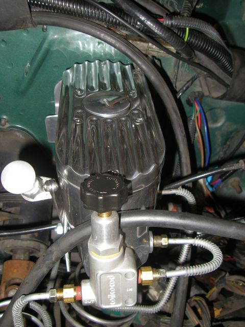 1990 Ford Bronco - A polished, finned aluminum reservoir with a black adjustment knob sits atop a Wilwood proportioning valve marked IN and OUT, plumbed with…